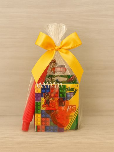 A small gift bag with colorful kids' items tied with a yellow bow.