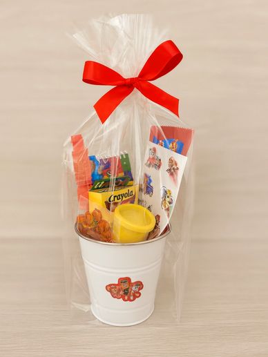 A white bucket gift pack with crayons, stickers, and a red bow.
