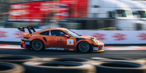 Orange race car speeding on a track with motion blur.