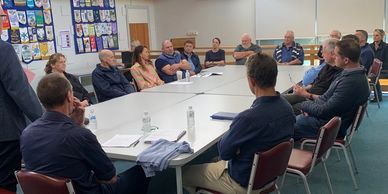 Group of people in a meeting sitting around a large table.