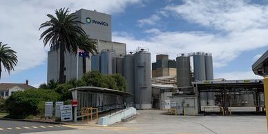 Industrial facility with PrevCo branding and palm trees under a partly cloudy sky.