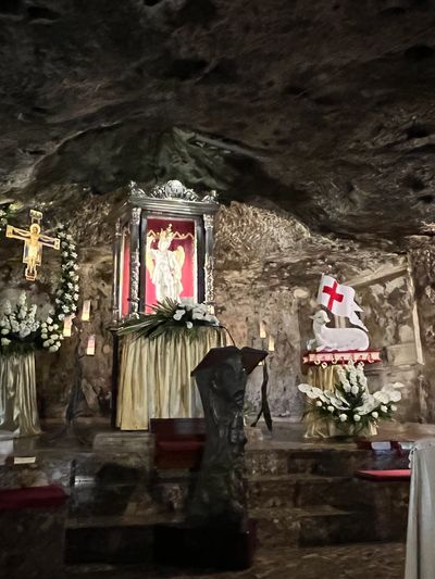 A religious altar inside a stone cave with statues and floral decorations.