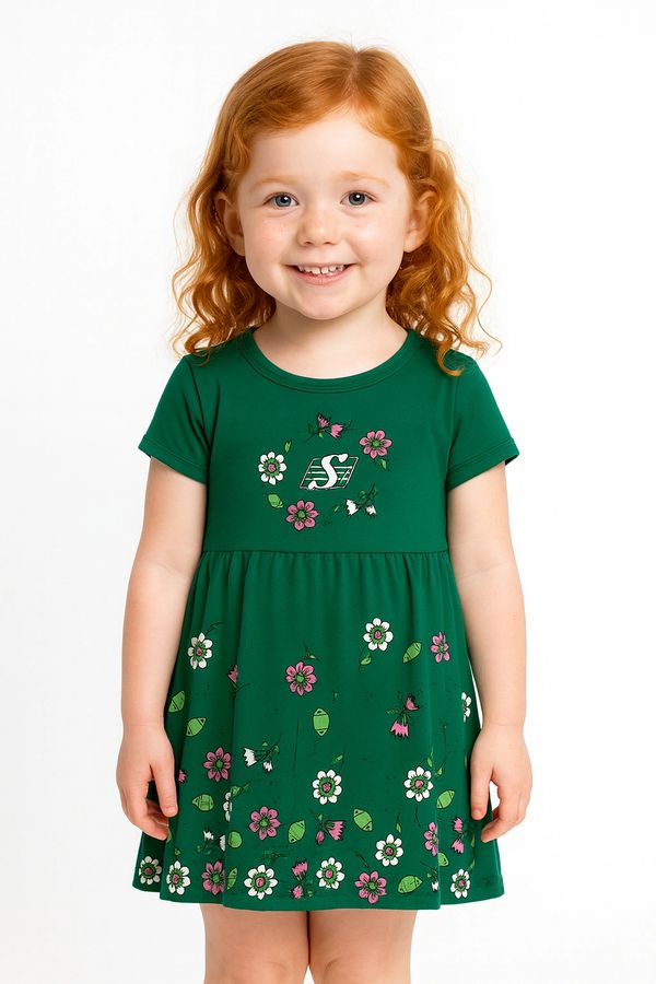 Smiling red-haired girl in a green floral dress.