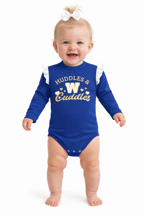 Smiling baby in a blue onesie with white ruffles and a bow, standing barefoot.