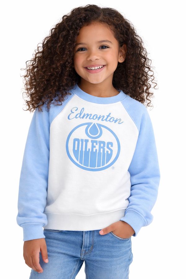 Smiling girl wearing Edmonton Oilers sweatshirt and jeans.