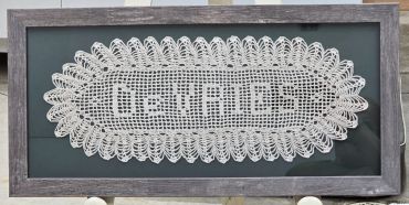 Crocheted doily with the word 'DOILIES' framed.
