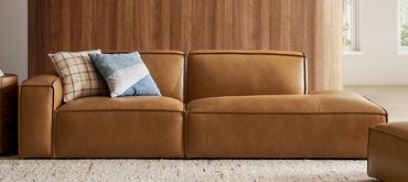 Modern brown leather sofa with cushions.