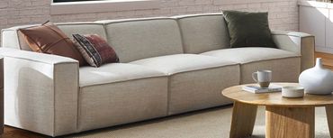 Modern beige sofa with colorful cushions.