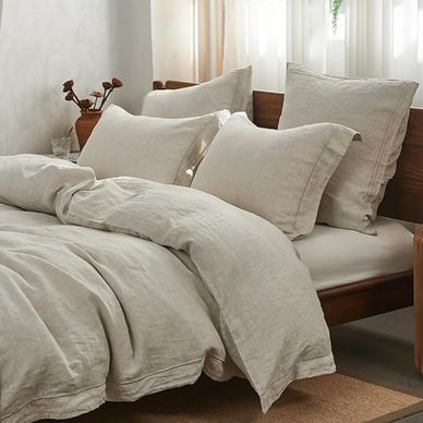 Cozy bed with beige linen bedding and pillows.