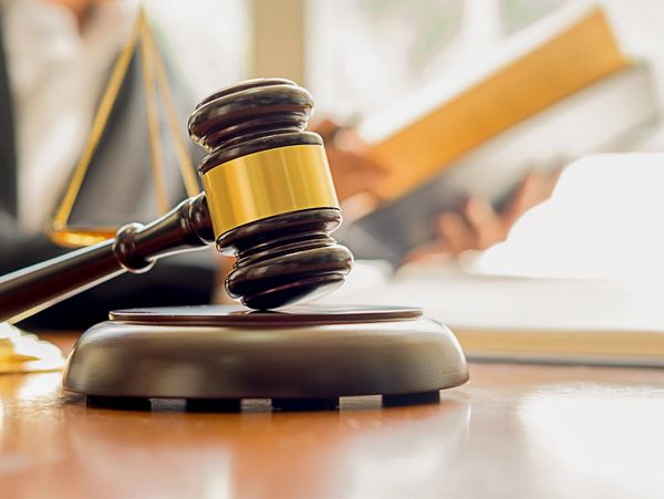 Close-up of a judge's gavel and scales of justice on a wooden desk.