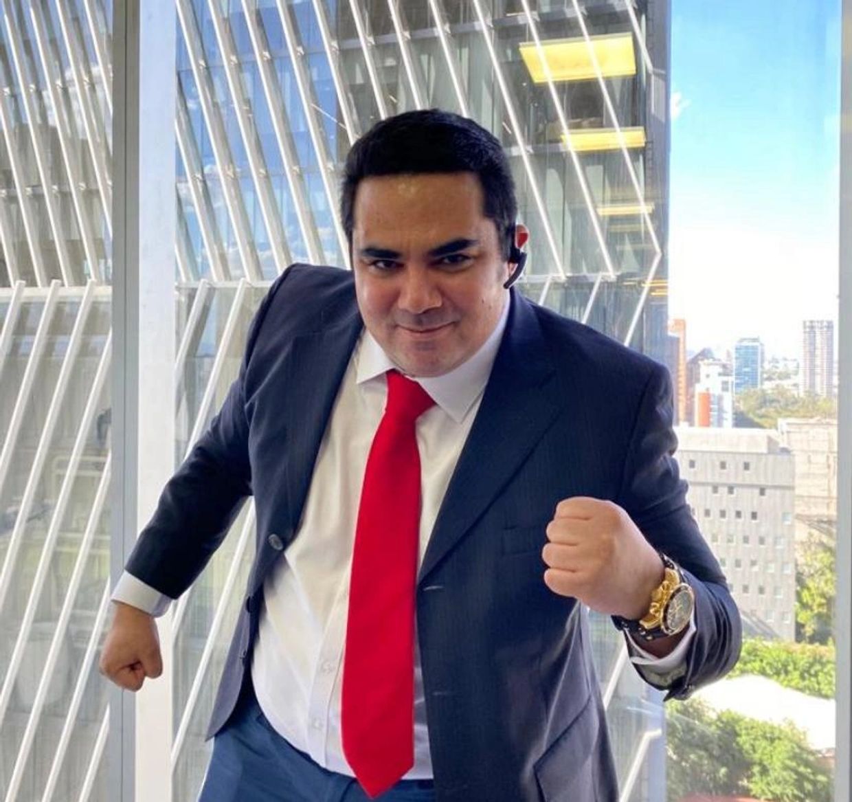 Man in suit with red tie posing confidently indoors.