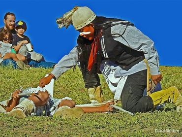 A family watches as a young Apache warriors perform the Deer Hunt dance.