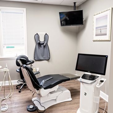 Modern dental examination room with equipment and chair.