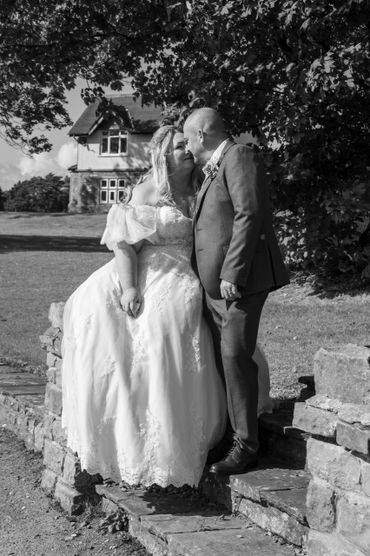 Bride and groom share a tender moment outdoors in black and white.