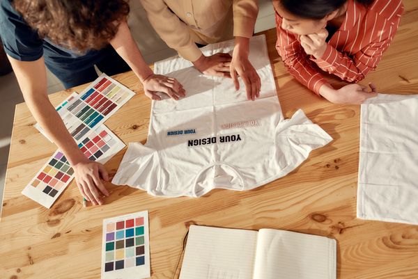 Three people collaborate on a custom t-shirt design.