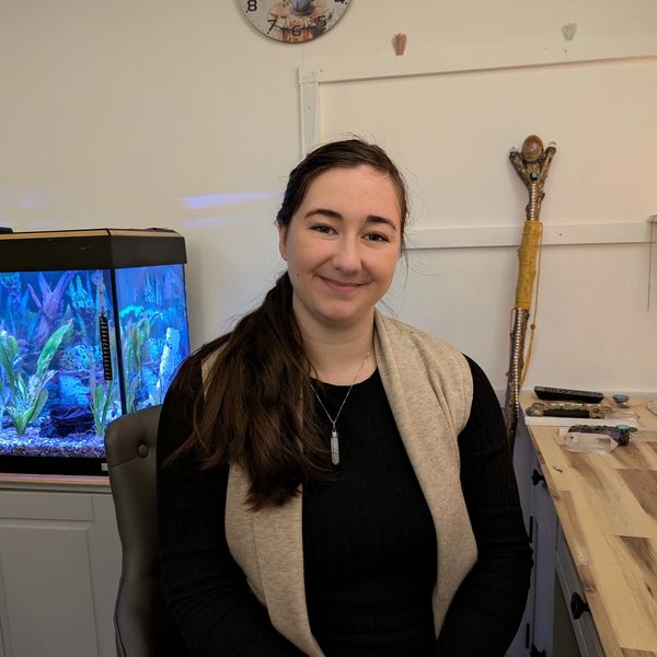 Smiling woman sitting in a room with an aquarium. Spiritual Healer