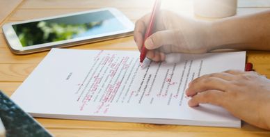 A person editing a text in red pen