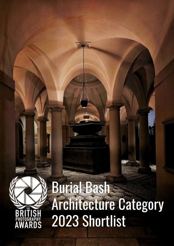 A solemn architectural interior with arches and columns, featuring a central tomb.