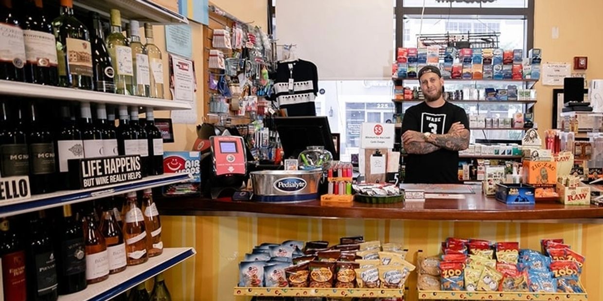 The owner of a local bodega stands proudly behind the counter