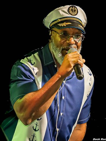 A man in a captain's hat singing into a microphone.