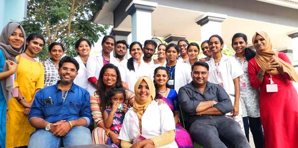 A diverse group of people posing together outdoors, smiling warmly.