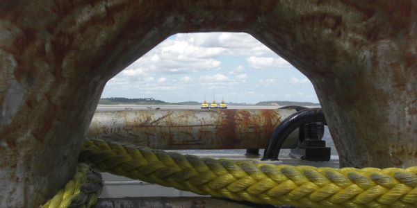 A view through a tug boat's capstan with towing cable on three tugs in the distance