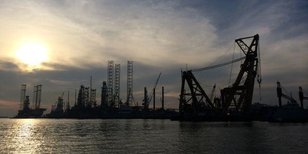 Oil rigs and heavy lifting sheerlegs at sunset in the port of Singapore