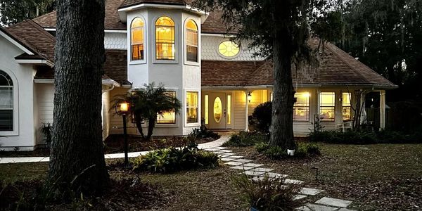 A cozy house at dusk with warmly lit windows and a stone pathway.