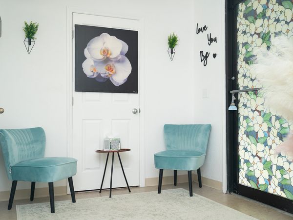 Minimalist waiting room with teal chairs and floral decor.