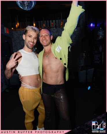 Two men posing cheerfully at a nighttime event with expressive outfits.