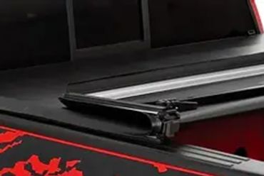 Red pickup truck with black and red graphic on the side and a partially open tonneau cover.