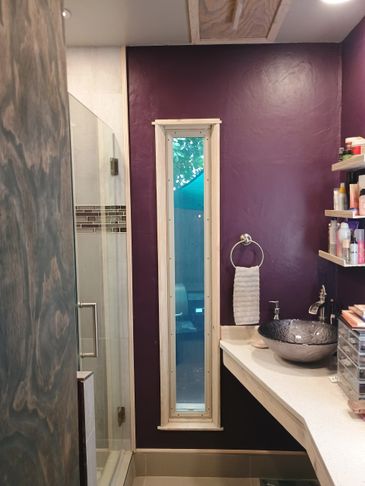 Narrow vertical window in a purple-walled bathroom with modern fixtures.