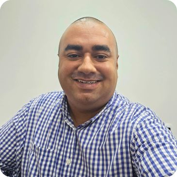 Smiling man in a blue and white checkered shirt against a plain background.