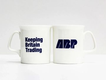 Two white mugs with the text 'Keeping Britain Trading' and 'ABP' in blue.