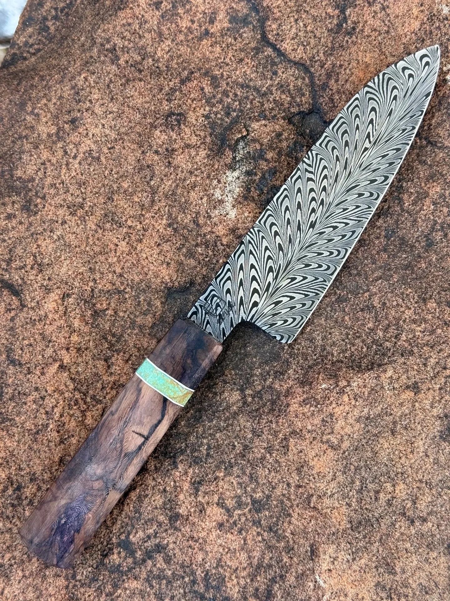 Etched Damascus blade on a classic wooden-handled knife.

