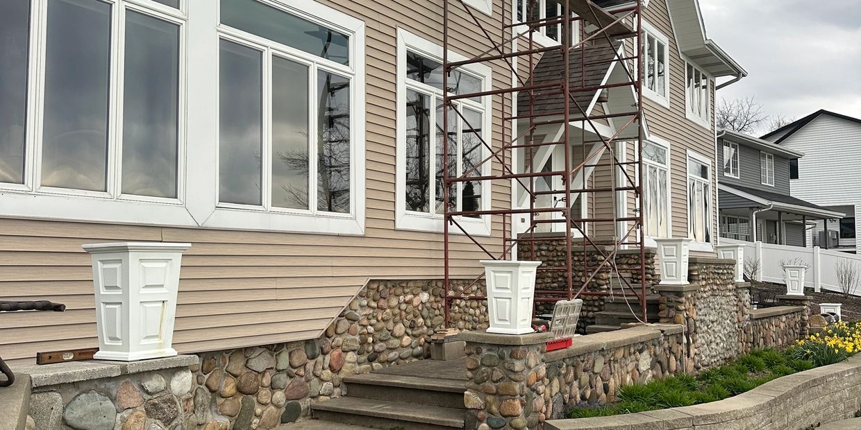 House exterior with stone foundation and scaffolding on front porch.
