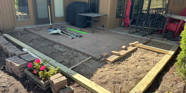 Backyard patio under construction with bricks and wooden frames.