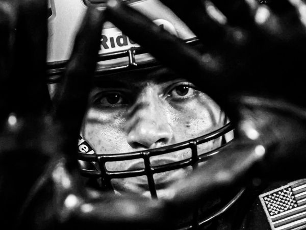 Close-up of a focused football player behind his helmet and gloves.