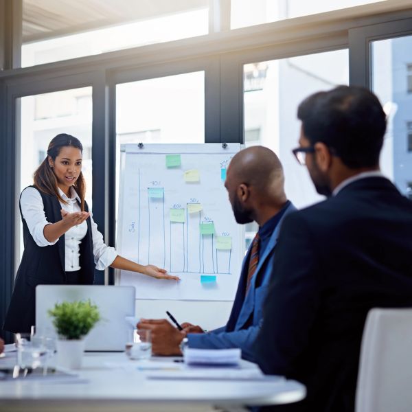 Businesswoman presenting bar chart to colleagues in a meeting room.