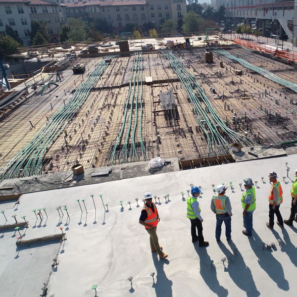 Construction workers inspecting a large concrete and rebar foundation site.