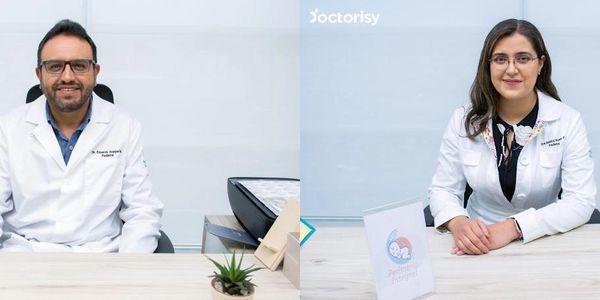 Two pediatric doctors sitting at their desks with friendly expressions.