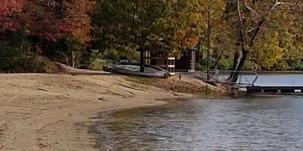 Calm lakeside with dock and autumn trees.