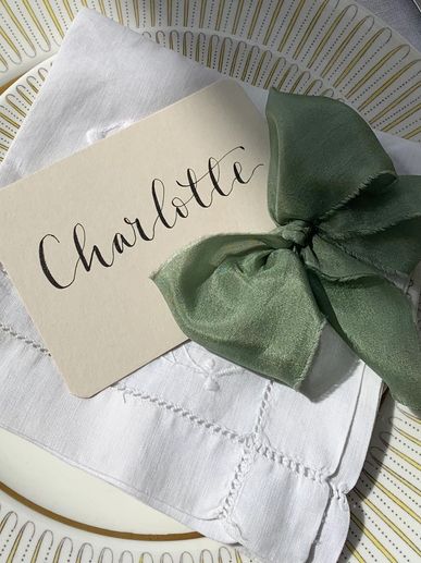 A flat name place card with calligraphy name and green silk bow.