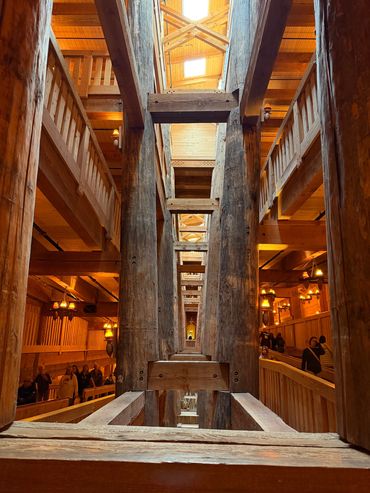 Inside a wooden structure with large beams and warm lighting.