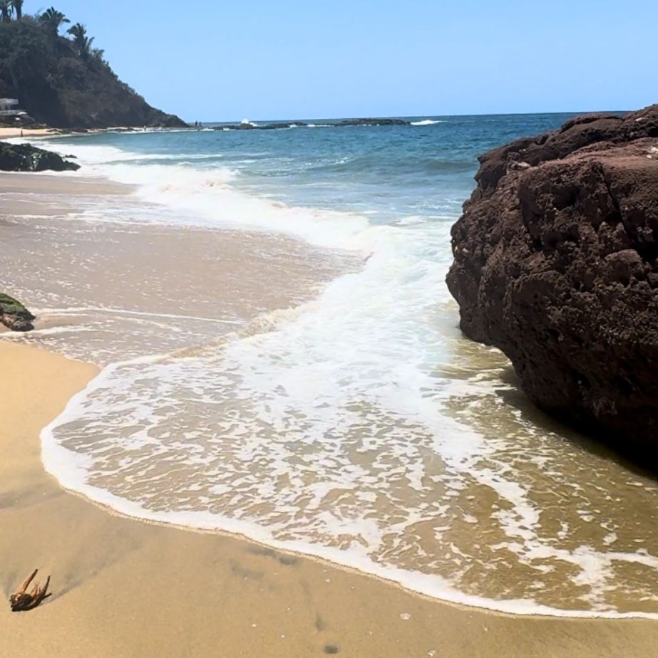 ocean with waves coming up and a big rocks around