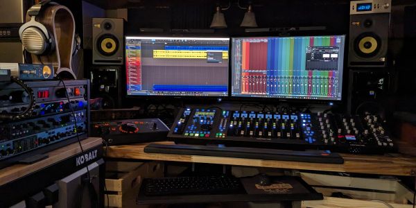 A professional music production setup with dual monitors and audio mixing equipment.