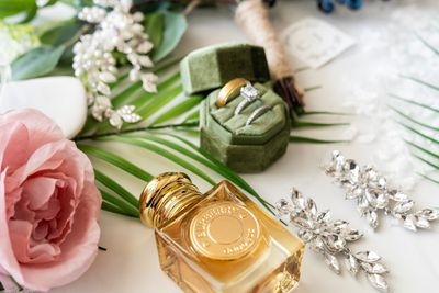 Wedding accessories including rings, perfume, earrings, and flowers.