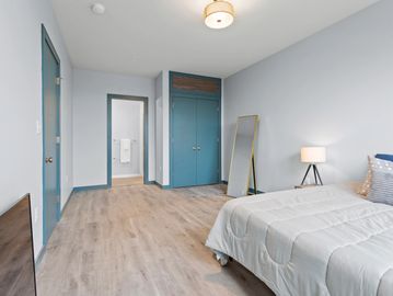 Minimalist bedroom with light blue walls and wooden flooring.