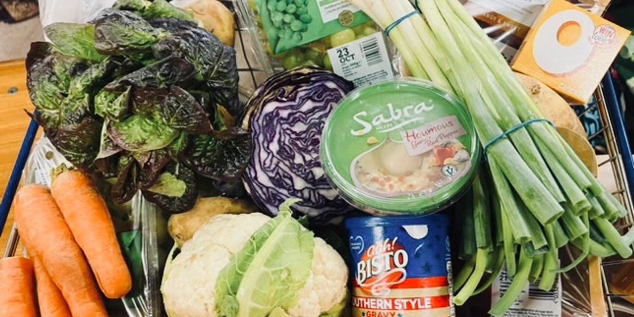 Fresh vegetables and food items in a shopping basket.