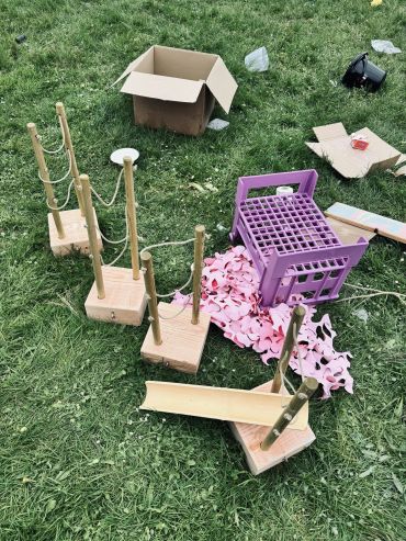 Wooden blocks, a purple crate, and cardboard on grass.